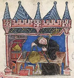 Enluminure d'un homme en habits de moine mesurant un disque doré posé sur une table avec un compas. Des livres et une mitre sont posés sous la table et la pièce se trouve dans ce qui ressemble à un château.