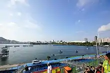 Photographie du Lagoa Rodrigo de Freitas lors des compétitions de canoë-kayak. Au premier plan, des gradins, à l'arrière-plan, la ville de Rio de Janeiro et ses immeubles.