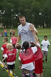 Un joueur de football américain entraîne des jeunes enfants et tape dans la main de l’un d'entre eux.