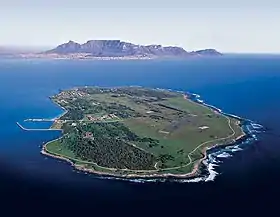 Vue aérienne de Robben Island, au second plan, la ville du Cap.