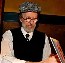photographie couleur d'un homme âgé portant une casquette et des lunettes