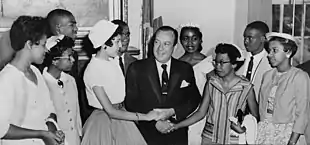 Photo en noir et blanc d'un homme congratulant neuf jeunes gens.