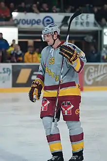 Robin Breitbach tenant sa canne en l'air avec la main gauche, sous le maillot de Genève-Servette