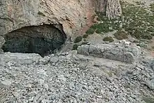 Entrée d'une caverne s'ouvrant au flanc d'une montagne rocailleuse