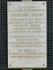 Plaque d'hommage de 1922 : « La bibliothèque de la ville détruite en 1870 par les projectiles allemands fut par lui reconstituée. Ses trois fils au cours de la Grande Guerre sont morts pour la France ».