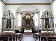 Vue intérieure de la nef vers le chœur avec les autels.
