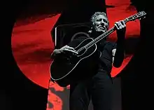 Photo en contre-plongée d'un homme vêtu de noir jouant d'une guitare elle aussi noire