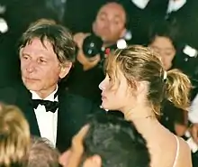 Roman Polanski et Emmanuelle Seigner lors d'un festival de cinéma au premier plan pris en photo par des photographes au second plan.