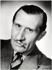 Photo en noir et blanc d'un quinquagénaire au visage long et à la moustache fine.