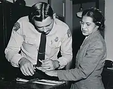 Rosa Parks et le shériff regardent la fiche des empreintes posée sur une table juste devant eux. Sans doute viennent-ils de la faire : le shériff tient fermement un doigt de Rosa Parks