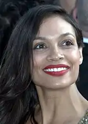 Photo en buste d'une femme souriante avec des cheveux longs noirs.