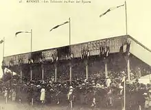 Photographie d'époque montrant la première tribune en bois construite au parc des sports de la route de Lorient en 1912.