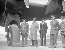 Le Premier ministre britannique, en uniforme et en compagnie d'autres hommes, à côté de la roue d'un avion.