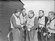 Photographie en noir et blanc d'un groupe d'hommes se saluant.