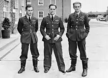 Photographie en noir et blanc de trois hommes en uniforme.