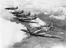 Photographie en noir et blanc de cinq avions de chasse monoplan volant en formation