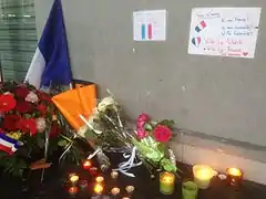 Dépôt de gerbes et de bougies allumées au pied du restaurant Quick sur la rue Jules-Rimet avec deux messages au mur (« Nous n'avons pas peur » et « Vous n’aurez ni ma France ! Ni mon humanité ! Ni ma fraternité ! Vive la liberté, vive la France, tous ensemble. »).