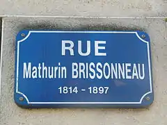 Plaque rectangulaire indiquant « rue Mathurin Brissonneau 1814-1897 » en blanc sur fond bleu.