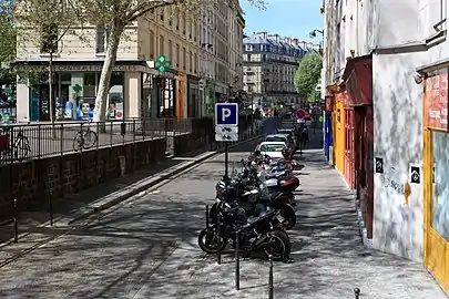 À droite, le niveau historique de la rue ; à gauche, l'élargissement réalisé lors du percement de la rue des Écoles.