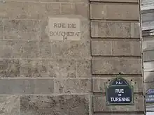 Ancien nom « rue Boucherat » gravé, et plaque avec le nouveau nom.