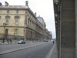 Le palais du Louvre, vu d’entre deux arcades de la rue de Rivoli. Celles-ci, à droite sur la photographie, sont du côté des numéros pairs.