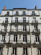 Façade en pierre blanche d'un immeuble de cinq étages, avec des balcons.