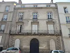 Façade en pierre grise d'un immeuble de trois étages.