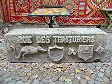 symboles de la rue, tarasque, blasons, sculptée sur une pierre en réemploi, en bord de rue