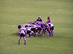 Photographie d'une mêlée dans un match de rugby à XV, entre l'équipe d'Écosse en maillots blancs et l'équipe de Roumanie en maillots bleus
