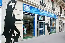 Vue de l'extérieur d'une boutique. Les murs proches de celle-ci sont décorés par des silhouettes d'actions de rugby.