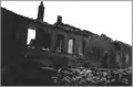 Ruines de l'école en mai 1940. Devant, le mur construit par le colonel Costa pour retenir les fuyards.