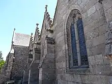 Photo d'un mur d'église en granite, avec trois gargouilles