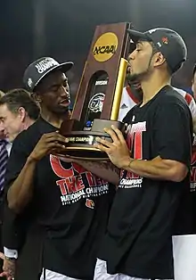 Deux joueurs tenant et regardant le trophée, l'un des deux l'embrassant.