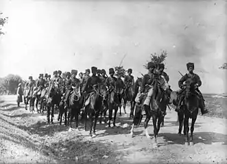 Photo noir et blanc d'une troupe militaire chevauchant sur une plaine.