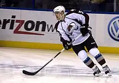 Photographie d’un joueur de hockey sur glace, de face, en pied, avec son équipement