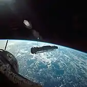 Photographie couleur du vaisseau spatial Agena dans l'espace avec la Terre en arrière-plan.