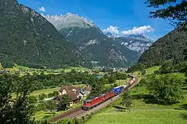 Locomotives Re 4/4 II et Re 6/6 tirant un train de marchandises sur la ligne du Gothard en s'éloignant de la commune de Erstfeld, visible dans le fond de la vallée. Juin 2015.