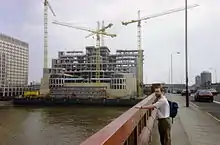 Un bâtiment en construction, au bord d'un fleuve, près d'un pont.