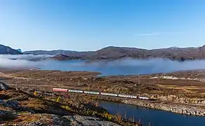 Le train Narvik-Stockholm, après Katterjåkk, allant vers Vassijaure, à la frontière entre la Norvège et la Suède. On devine, dans la brume, la ville de Riksgränsen et le lac de Vassijaure. Septembre 2017.