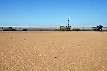 Épave d'un navire au milieu d'une plage de sable.