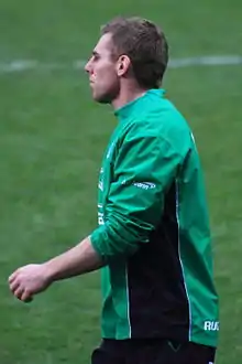 Portrait de profil en en demi grandeur d'un joueur de rugby portant un maillot vert