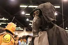 Homme portant un masque avec une trompe et une capuche noire.