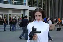 Femme portant une robe blanche et un pistolet.