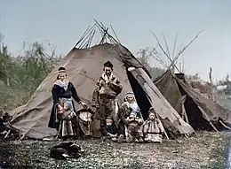 Famille samie vers 1900 devant une goahti de toile au 1er plan et une lavvu en arrière-plan.