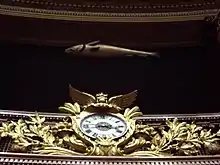 Sculpture d'un poisson suspendue au-dessus d'une horloge.