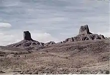 paysage de désert, à l'arrière plan deux sommets pierreux.