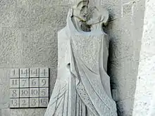 Façade de la  Passion à la Sagrada Familia : le baiser de Judas et un carré magique illustrant le nombre 33 (âge du Christ à sa mort).