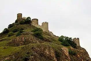 Photo d'un château en ruines se découpant sur un ciel gris.