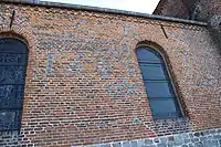 Inscriptions en briques surcuites sur le mur du chœur : initiales C B et la date 1683.