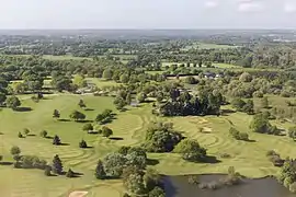 vu aérienne de parcours de golf, entouré par la campagne.